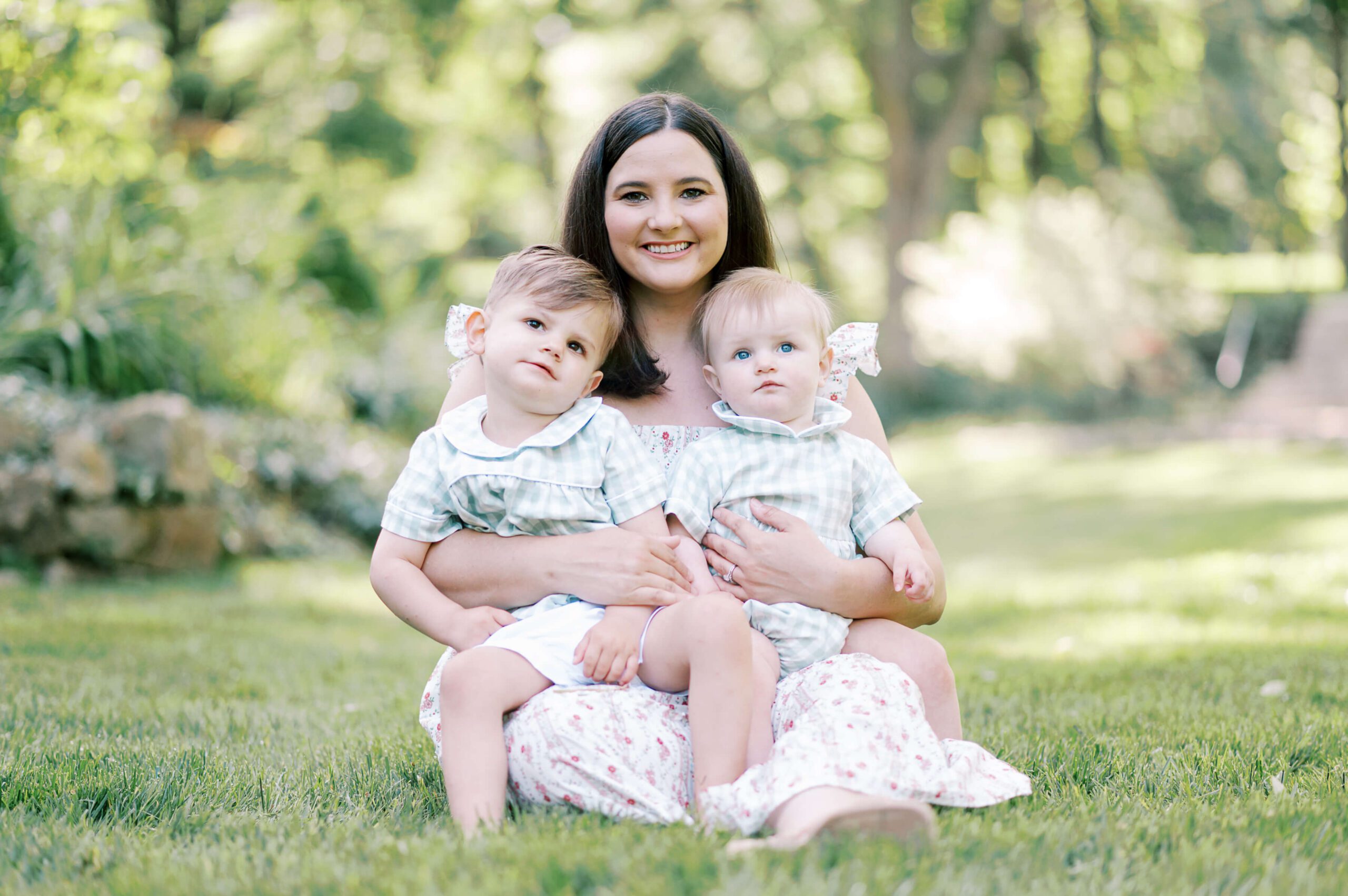 mom holding two toddler boys in green grass
