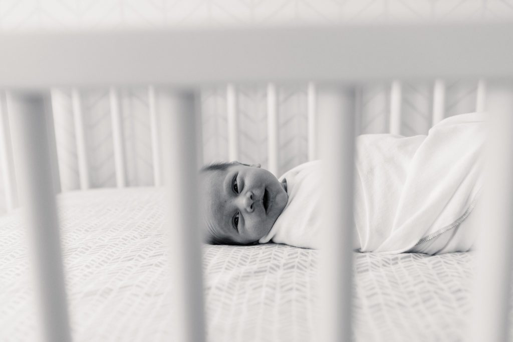 newborn baby girl swaddles in crib
