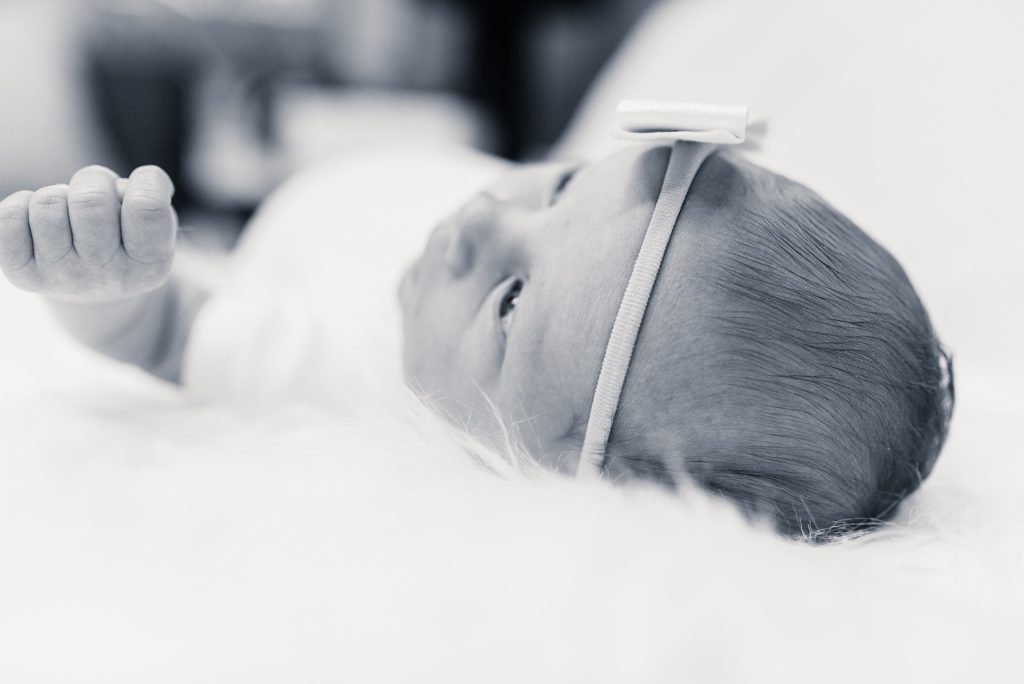 newborn baby girl in white onesie