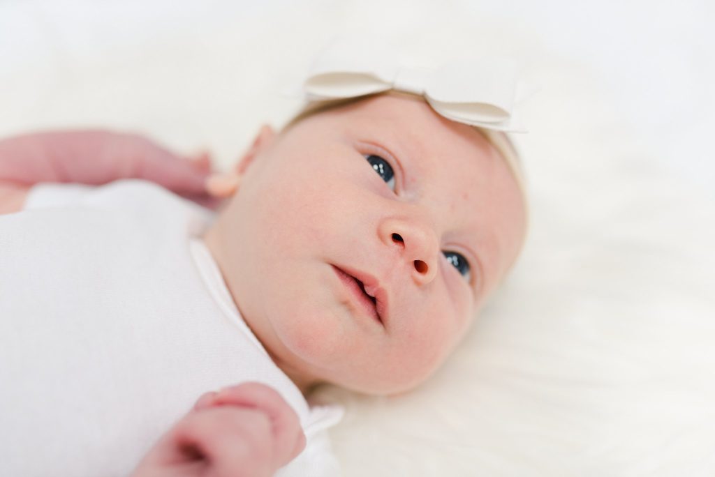 newborn baby girl in white onesie