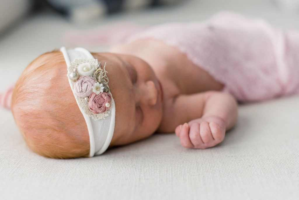 newborn baby girl in pink wrap and white embroidered headband