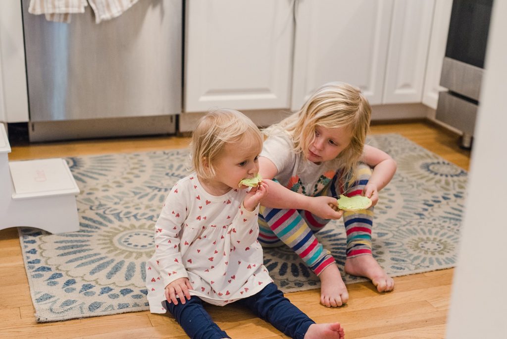 sisters eating cookies on kitchen floor
