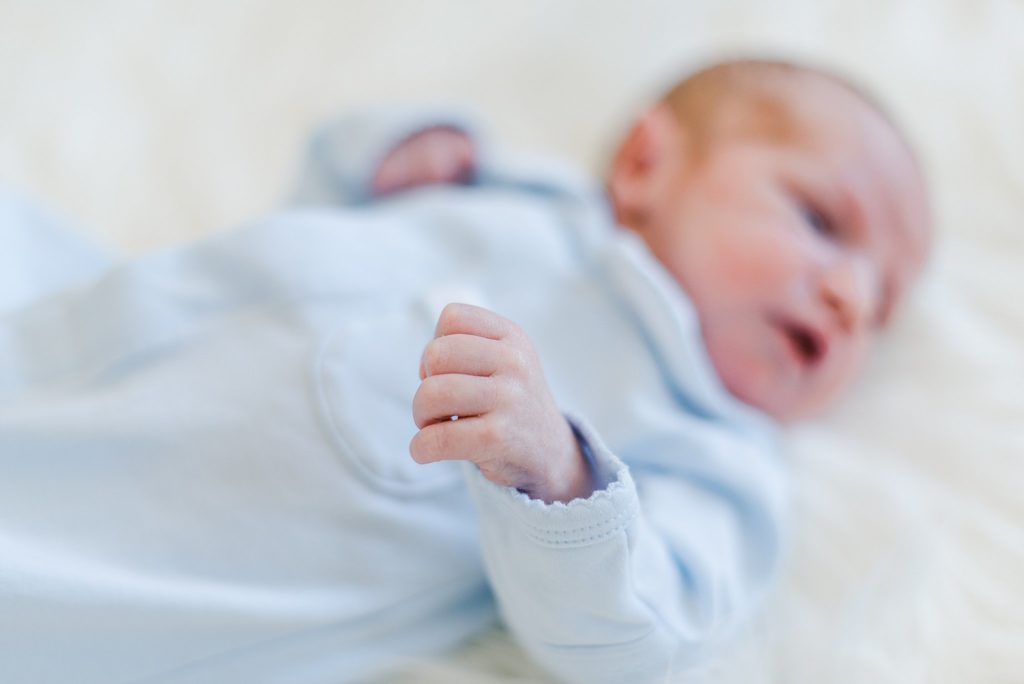 newborn baby boy in blue and white blanket in crib