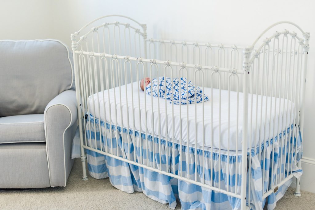 newborn baby boy in blue and white blanket in crib