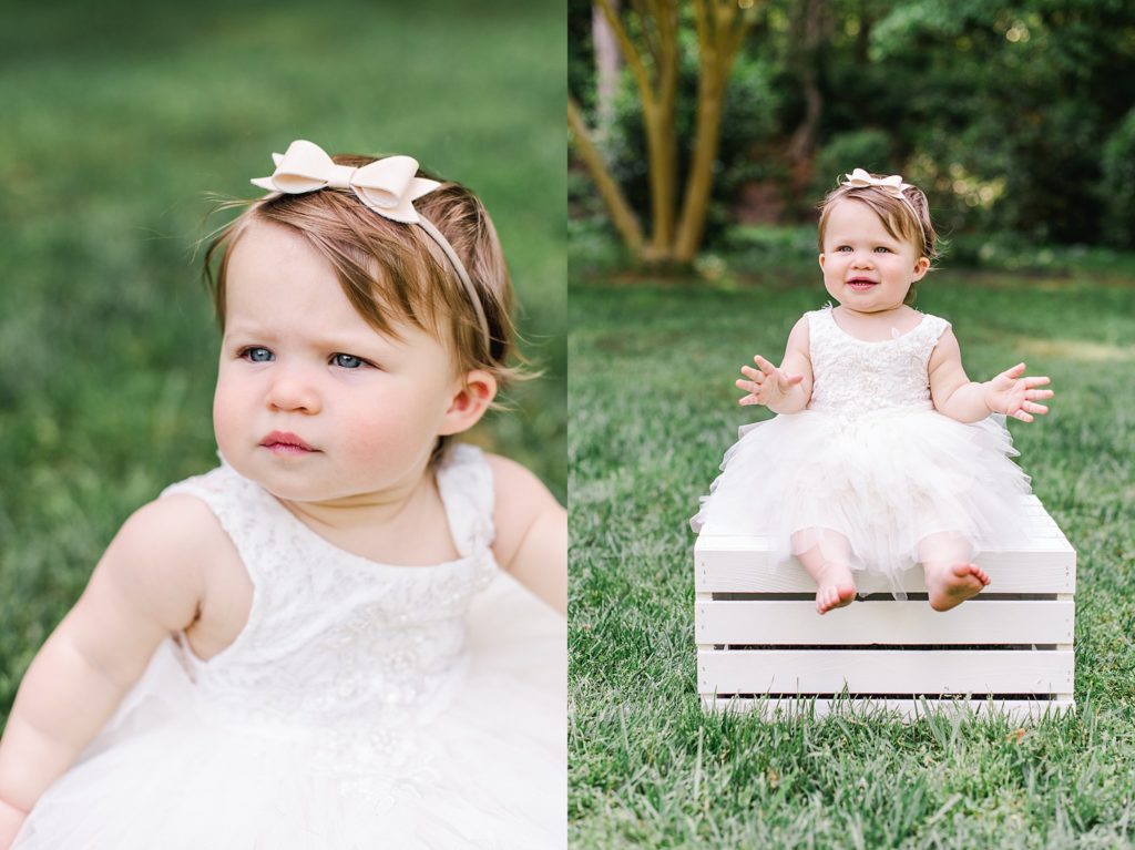 one year old girl in white dress on white wooden box