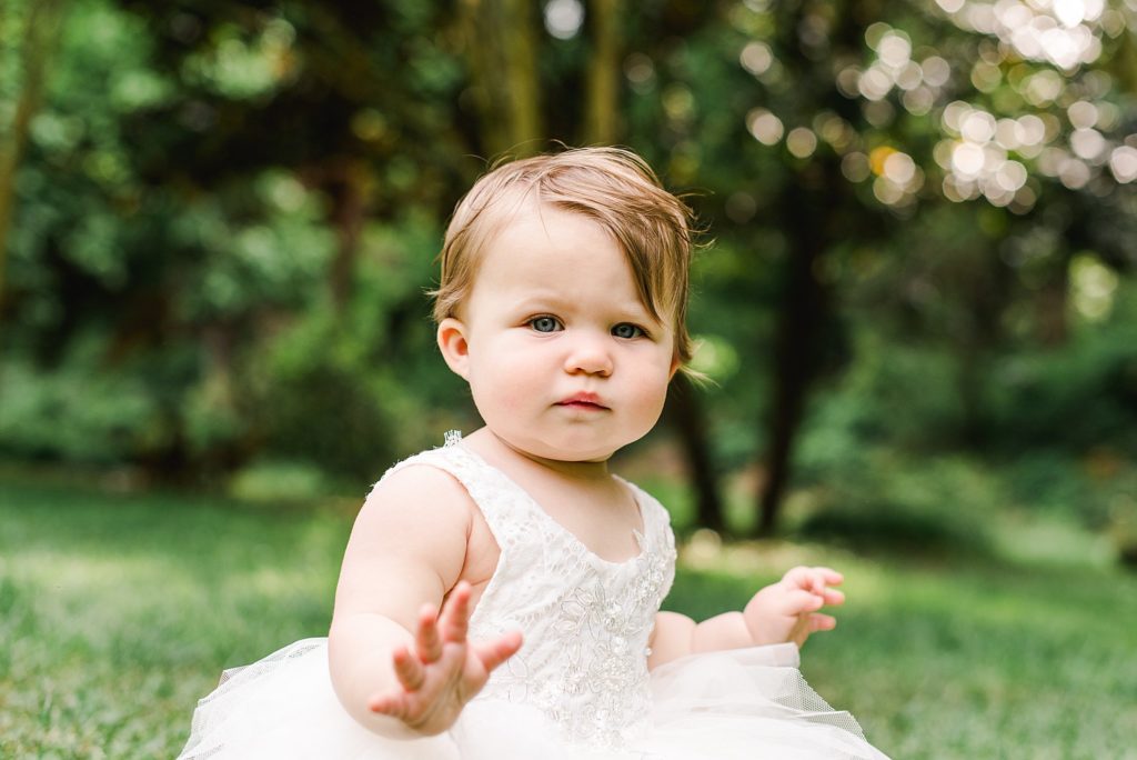 one year old girl in white dress in field