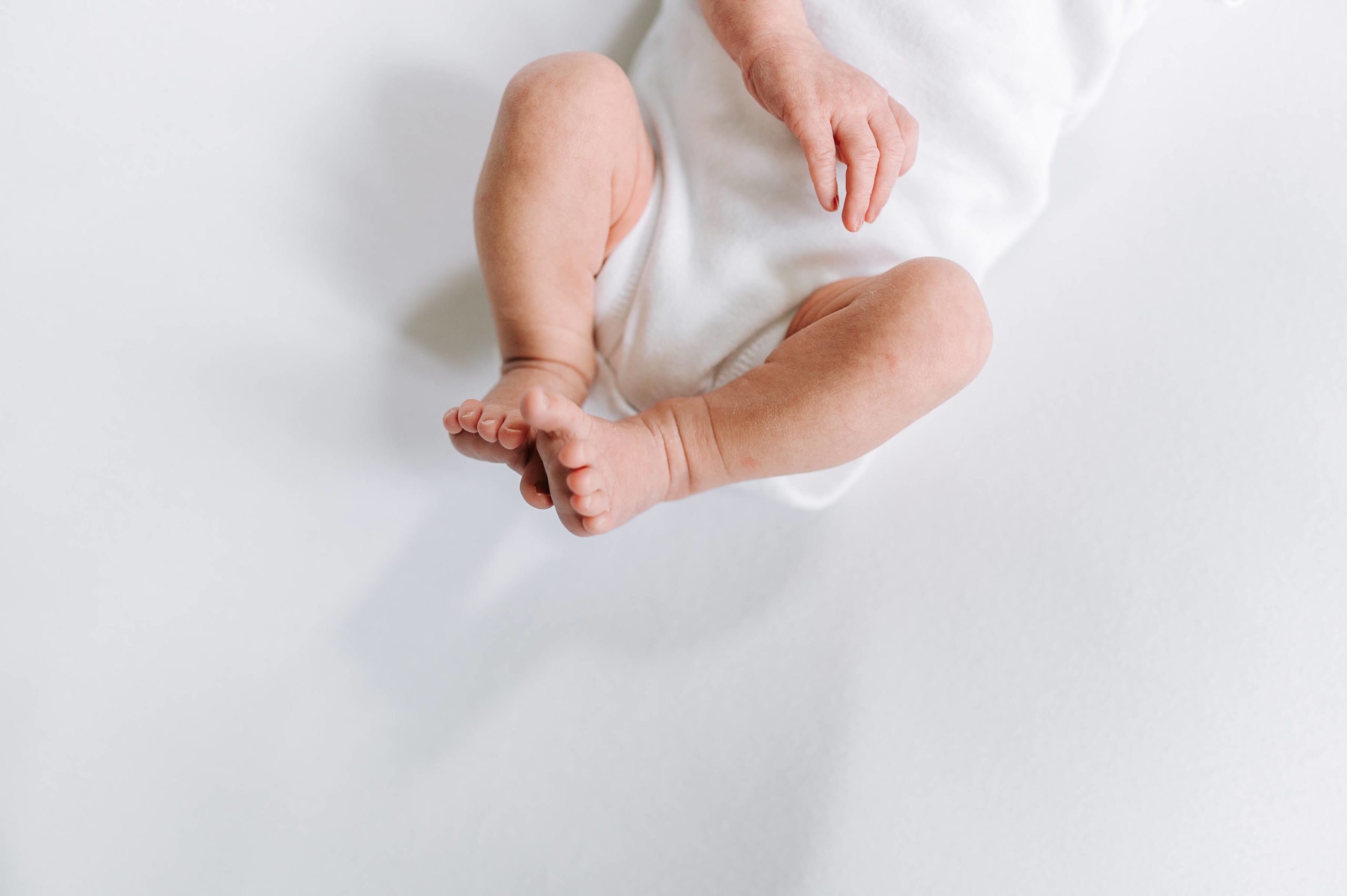 baby wearing white bodysuit with wiggly fingers and toes
