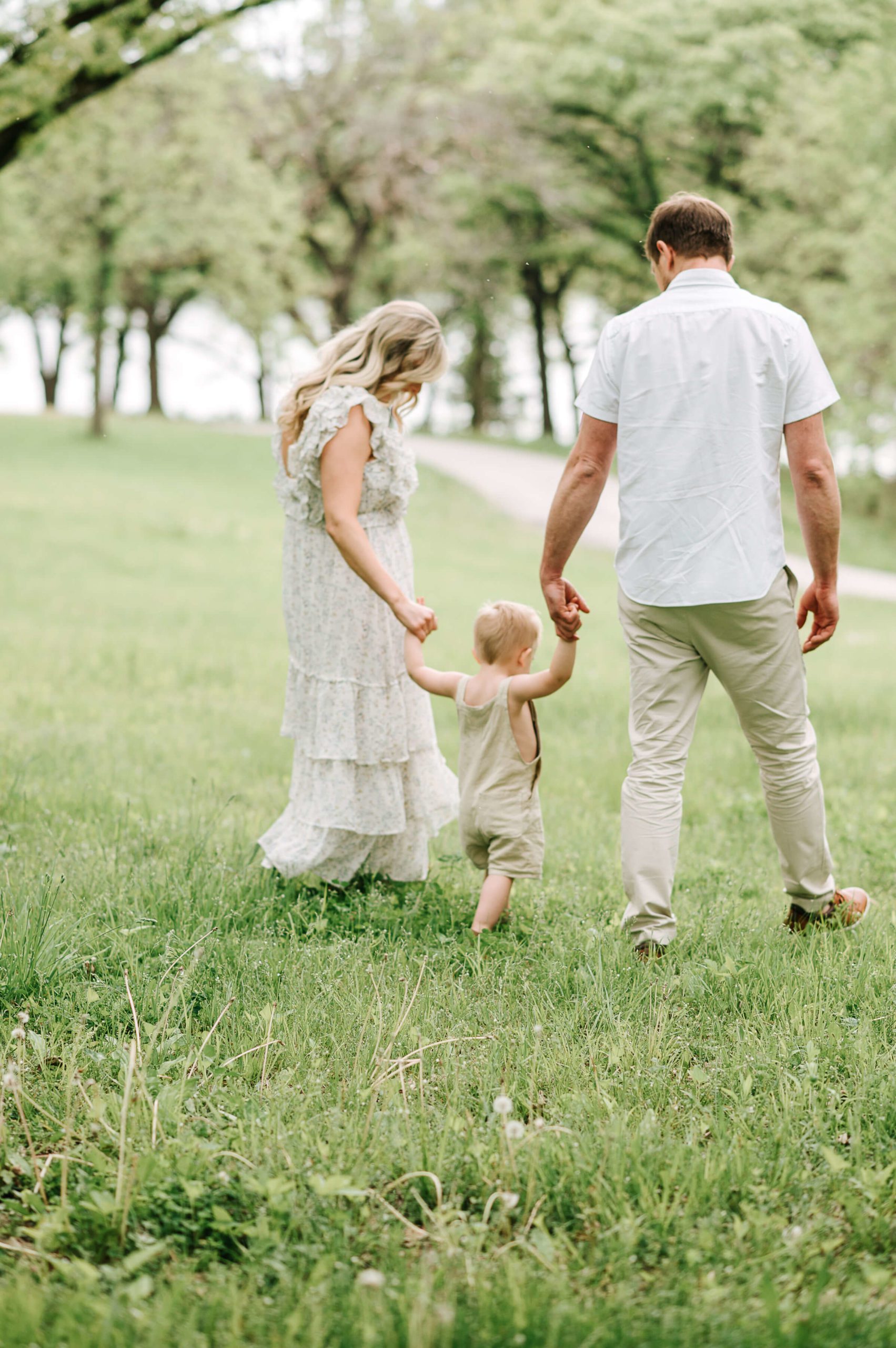 Family holding hands walking across grassy field