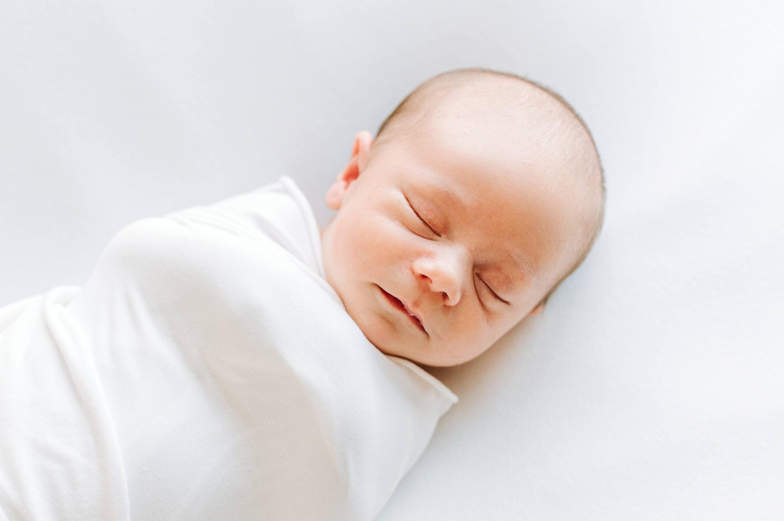 Newborn baby in white swaddle